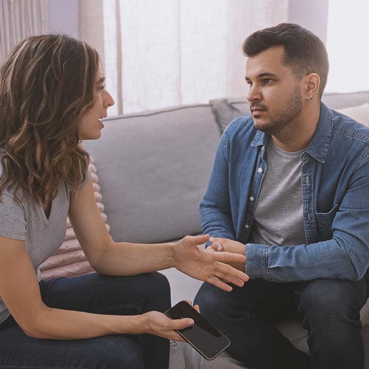 A young couple having a serious discussion on a couch.
