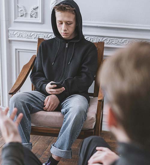 Support Your Teen Family Member A father has a serious conversation with his teen son, while the son pretends to ignore him